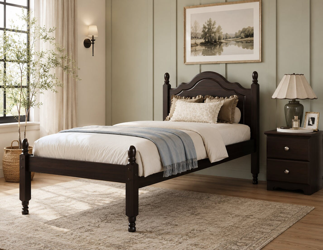 A dark brown wooden bed frame with a curved headboard and turned legs, styled with white bedding, a blue throw blanket, and neutral pillows in a beautifully decorated bedroom.
