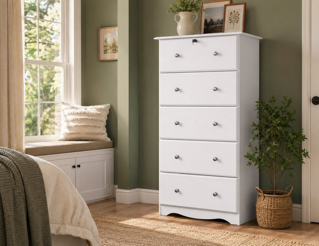 A tall white five-drawer dresser in a styled bedroom setting with sage green walls, a window with a bench seat, and potted plants.